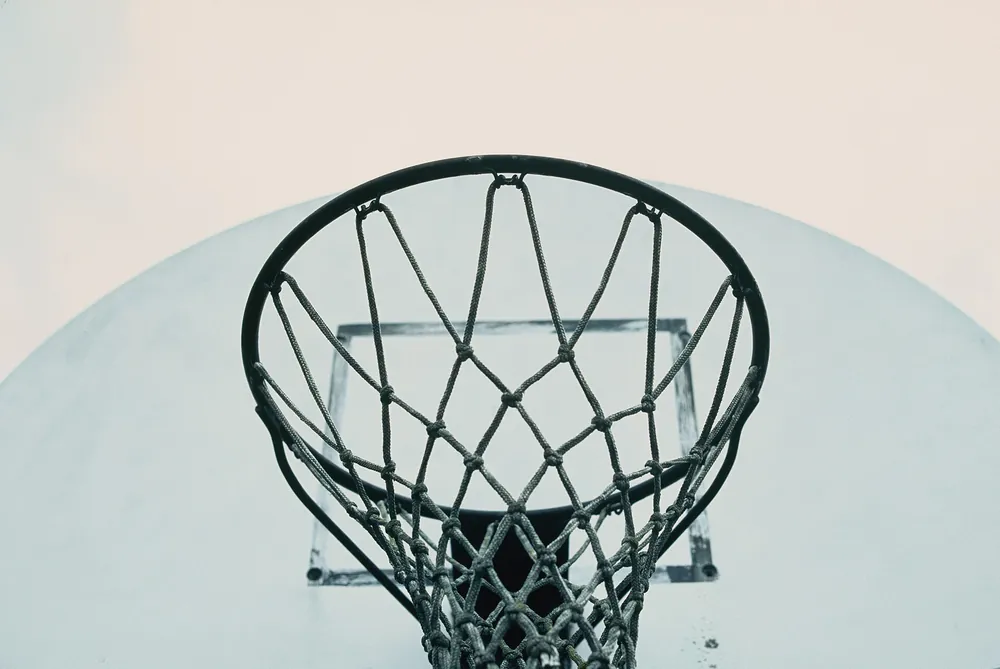 Cesto de basquetebol e rede vistos de baixo contra um fundo claro
