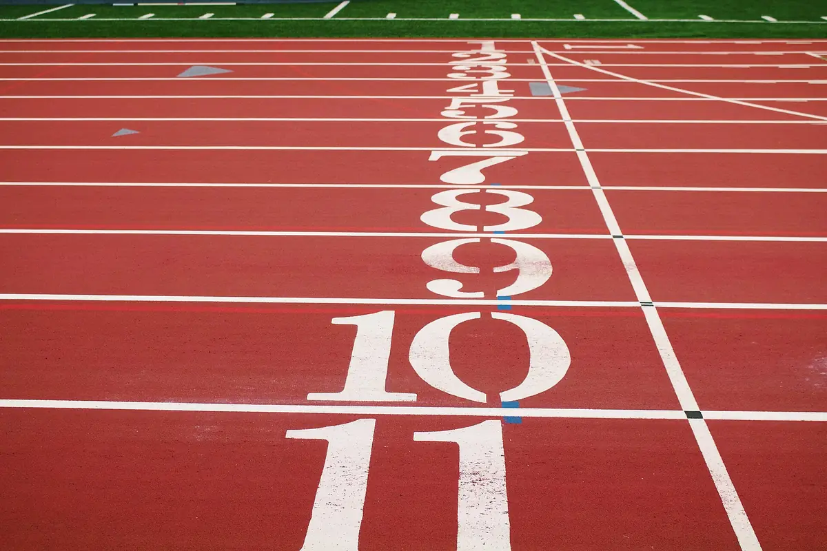 Corredores numerados de uma pista de atletismo vistos de cima