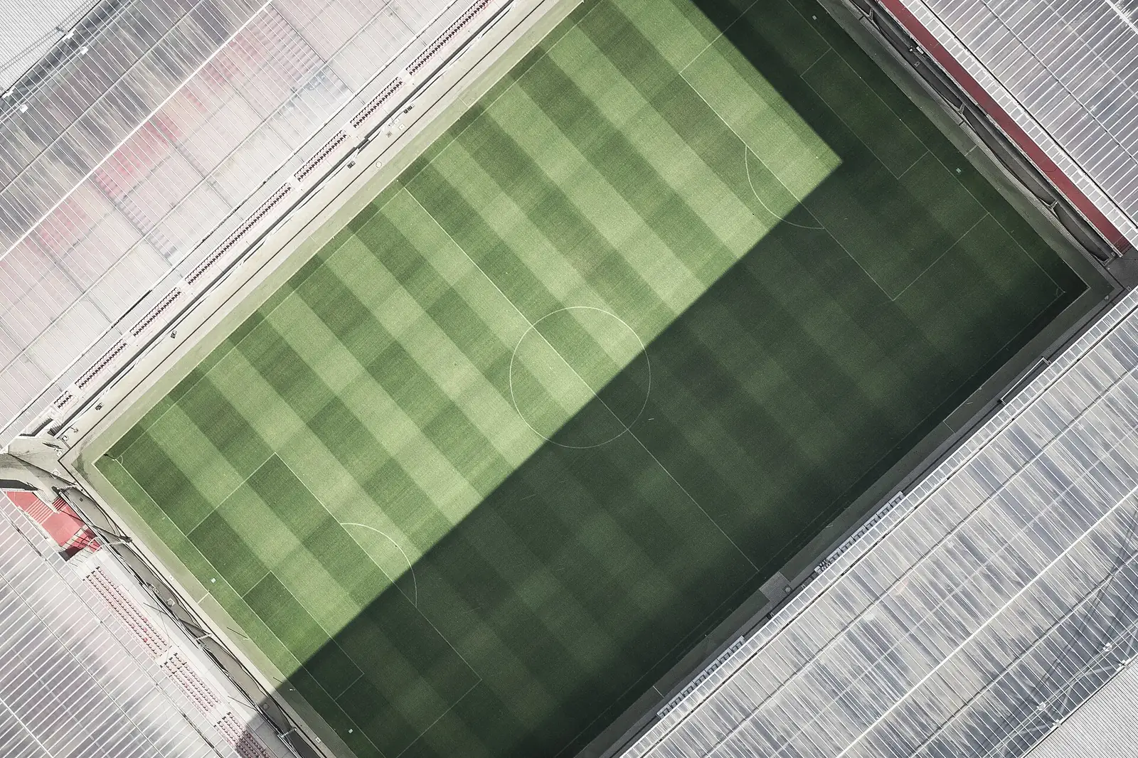Vista aérea de um relvado com marcações brancas e bancadas em redor