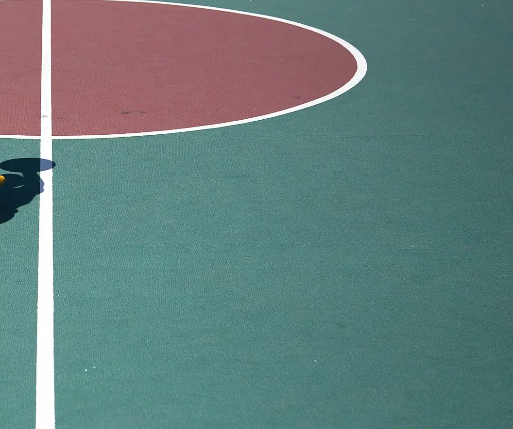 Piso de um recinto exterior de basquetebol com o círculo central e linhas brancas pintadas
